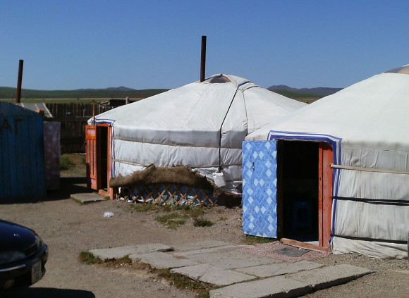 PHOTO: Two Mongolian ger, semi-permanent, circular tent structures, complete with welcome mats at the doors.