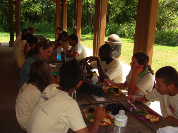 PHOTO: Staff and crew feast at picnic tables in the shade on a sunny day.