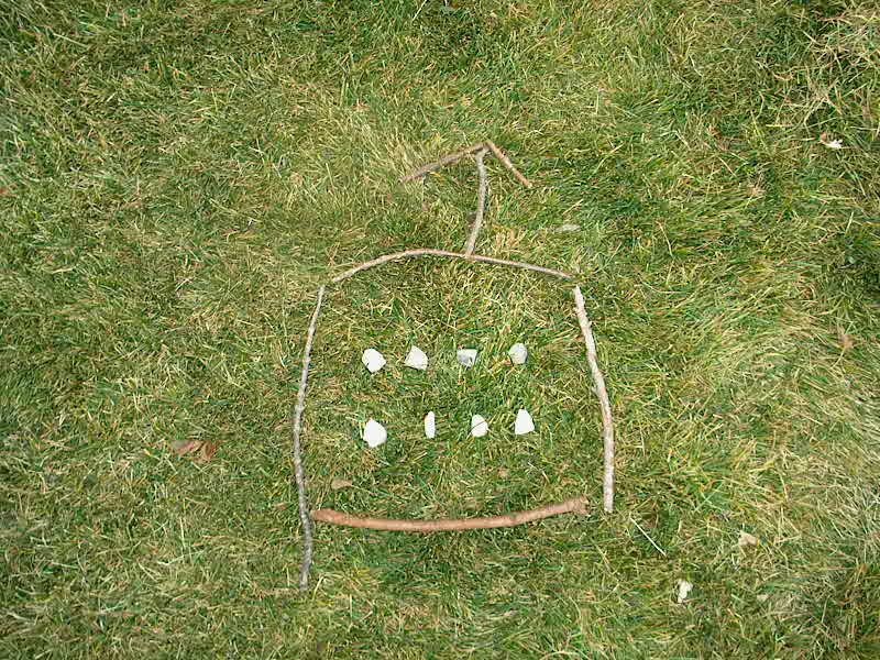 PHOTO: four sticks are arranged to form a square with eight stones inside the square; three sticks form an arrow over the square to tell what direction the hiker should take.