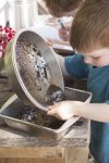PHOTO: A young boy mixes mud in kitchen baking pans.