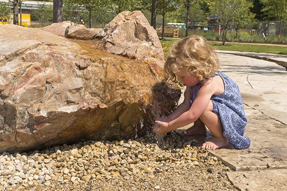 PHOTO: A young visitor discovers the boulder bubbler at the Nature Play Garden.