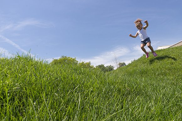PHOTO: A little girls jumps on the rolling hills at the Nature Play Garden.