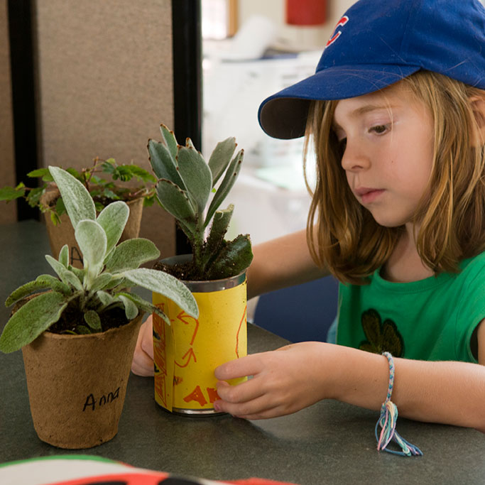 PHOTO: a young girl decorates plant pots to give as teacher gifts.