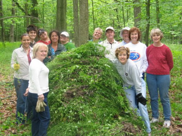 Garden volunteers pose with a pile of removed garlic mustard at an annual "garlic mustard pull" event.