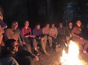 PHOTO: the scholars in the program are sitting around a campfire at night.