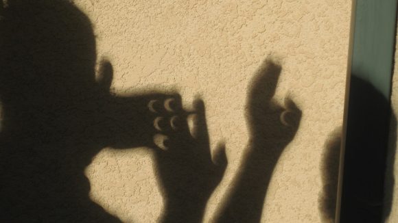 Eclipse shadows seen through crossed fingers of kids.